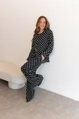 Camisa negra con estampado de lunares blancos, de manga larga y cuello clásico.