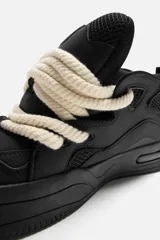 Zapatillas negras de skate con cordones gruesos tipo cuerda, lengüeta acolchada y suela con volumen.
