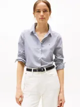 Camisa de popelina a rayas verticales azules y blancas, de corte regular, con cuello inglés y puños con botón. Logo de Tommy Hilfiger bordado en el pecho.