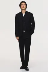 Blazer negro de tejido suave con solapas de muesca finas y ojal decorativo. Modelo de botonadura sencilla con un botón visible, bolsillo superior insertado, dos bolsillos delanteros con solapa y tres bolsillos interiores. Posee botones decorativos en los puños y abertura doble en la espalda. Corte ajustado.