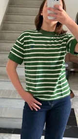 Remera verde con rayas horizontales blancas, cuello redondo y mangas cortas con puños.