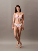 Conjunto Calvin Klein Modern Cotton color rosa pálido, compuesto por un corpiño triángulo con copas sin relleno y una bombacha tipo bikini. Ambos con banda elástica blanca con logo de la marca.