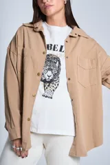 Sobrecamisa color beige de gabardina con cuello camisero, cierre frontal con botones a presión, dos bolsillos de parche en el pecho y corte holgado.