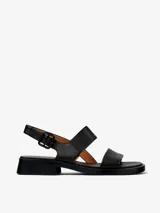Sandalias de cuero vacuno color negro, con dos tiras anchas sobre el empeine, tira trasera con hebilla ajustable y suela baja con pequeño taco cuadrado.