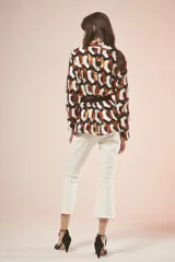Saco con estampado geométrico en tonos blanco, negro y naranja, con cuello en V, mangas largas y lazo negro para ajustar en la cintura.
