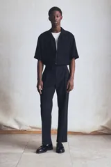 Pantalón de vestir negro de corte recto, confeccionado en mezcla de lino y algodón. Cuenta con cierre frontal con botón y gancho ocultos, bolsillos laterales y traseros ribeteados, pinzas y pliegues delanteros y traseros.