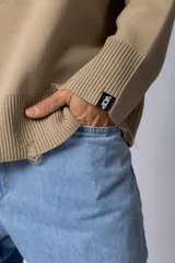 Sweater beige de hilo de algodón, corte oversize, con cuello redondo, puños y ruedo acanalados con pequeños desgastes. Espalda con logo tejido.