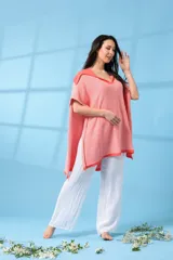 Poncho tejido de hilo color salmón con cuello en V y terminaciones en color coral.