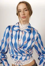 Camisa crop con cintas para cruzar en la cintura, con estampado de rayas onduladas azules y blancas con medusas rosadas.