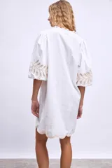 Vestido blanco de lino con escote en V, mangas cortas abullonadas y bordados florales en beige en mangas y ruedo.