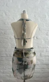 Vestido corto de microtul con estampado abstracto en tonos beige, marrón, verde y celeste. Diseño ajustado con escote halter y espalda descubierta.