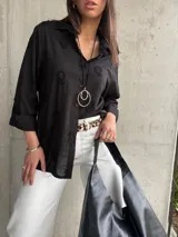 Camisa negra con bordados, de corte clásico y manga 3/4.