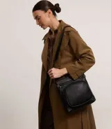 Bolso tipo postman negro, confeccionado en poliuretano, con bolsillo delantero y correa ajustable.