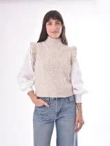 Chaleco tejido color beige con cuello alto y volados en los hombros. Diseño con patrón de rombos en relieve.