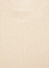 Chaleco de punto color crema, con cuello redondo y diseño sin mangas. Ajustado al cuerpo y con cinturón fino de cuero marrón.