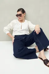 Pantalón de jean azul oscuro, de corte ancho y tiro alto, con bolsillos delanteros cuadrados y amplios.