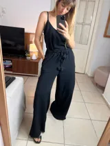 Mono negro de breteles finos con cintura elastizada y lazo ajustable. Pantalón palazzo de corte amplio.