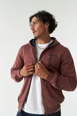 Campera de felpa color ladrillo con capucha ajustable, cierre frontal y bolsillos laterales con cierre. Tiene puños y logo bordado en la espalda.