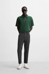 Pantalón slim fit negro confeccionado en tejido con elasticidad en ambas direcciones. Cuenta con bolsillos frontales y traseros de vivo con botón. Cierre frontal con cremallera y botón.