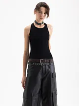 Top de punto acanalado color negro, ajustado al cuerpo y de largo por encima de la cadera. Presenta cuello redondo cerrado y breteles cruzados en la espalda. Confeccionado en hilado frío.