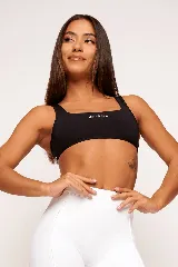 Top deportivo negro con breteles anchos y escote cuadrado. Estampado frontal con la palabra "Wellness" en color blanco.