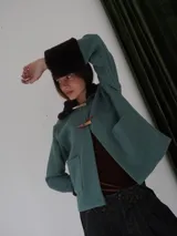 Campera corta negra con cuello y puños de piel sintética negra. Cierre con presillas de madera.