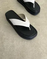 Ojotas negras con base cuadrada y tiras blancas.