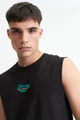 Musculosa negra de algodón con corte oversize y estampado en turquesa en la espalda con la frase "Good things Never come from Comfort Zones" y el logo de la marca Mistral.