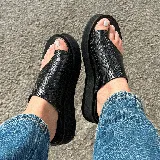 Sandalias negras de cuero con plataforma y tira ancha sobre los dedos.