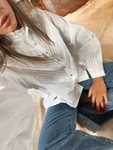 Camisa blanca de mangas largas con cuello alto y detalles de encaje.