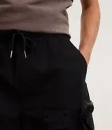 Bermuda color crema de poliéster, corte baggy cropped, con cintura elástica ajustable con cordón y bolsillos cargo funcionales.