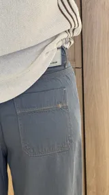 Pantalón ancho color verde oliva, de tiro alto y corte holgado. Confeccionado en mezcla de algodón y lino, con pinzas debajo de la rodilla, bordado de monograma en el bolsillo delantero y pespuntes a contratono.