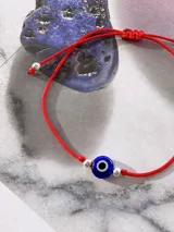 Pulsera roja regulable con cierre nudo macramé, con ojito turco azul y cuentas plateadas.
