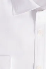 Camisa blanca de manga larga texturizada, tejida en dobby, con cuello italiano y cartera abotonada. Tiene un logo bordado en el pecho.