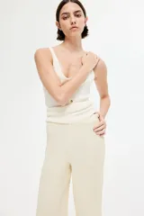 Pantalón de corte holgado color crema, confeccionado en tejido de punto con textura. Modelo de tiro alto con cintura elástica y piernas rectas.