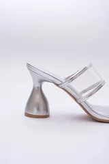 Sandalias plateadas con taco de forma geométrica y tiras transparentes.