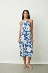 Vestido midi con estampado abstracto en tonos naranja y blanco, breteles finos y corte evasé.