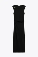 Vestido midi negro de punto, con cuello asimétrico, manga sisa, aplique metálico dorado en el hombro y drapeado lateral.
