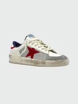 Zapatillas Golden Goose modelo Stradan, de cuero blanco con detalles en gris y rojo. Presentan una estrella roja de gamuza en el lateral, puntera de gamuza gris, detalles de mesh plateado y talón azul.