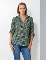Blusa de gasa con estampado geométrico en tonos verdes, azules y morados. Presenta cuello con solapa, escote en V con botones y mangas largas que se pueden remangar y sujetar con presilla.