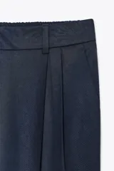 Pantalón azul marino de tiro alto con bolsillos delanteros y terminación con vuelta en el ruedo. Cierre frontal con cremallera y botón.