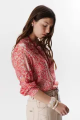 Camisa roja con estampado floral, cuello en V y mangas largas con puños abotonados.