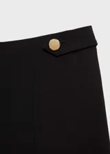 Pantalón azul marino de tiro medio y corte recto, con detalle de botones decorativos en la cintura y cierre frontal con botón, gancho y cremallera. Diseño crop.