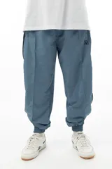 Pantalón de jogging celeste de tela avión con forro interior de red y banda lateral negra.