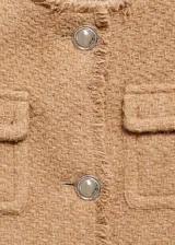 Chaqueta corta de tweed color marrón con cuello redondo, cierre frontal con botones metálicos, cuatro bolsillos de parche y terminaciones deshilachadas.