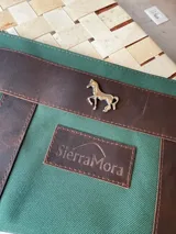 Sobre tipo cartuchera color borgoña, de lona con terminaciones en cuero marrón. Tiene cierre superior y aplique de cuero con el logo de la marca.