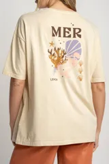 Remera color arena de algodón peinado, corte oversize y manga corta. Estampado pequeño de una concha en el pecho.