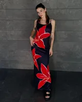 Vestido largo negro con estampado de flores rojas, de tirantes finos y corte al cuerpo.