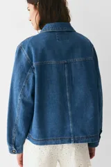Campera azul de denim con cuello clásico, cierre frontal con botones dorados, dos bolsillos de parche en el pecho y dos bolsillos ribeteados en la cintura.