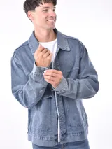 Campera de jean celeste con corte recto, cuello clásico, cierre frontal con botones metálicos, bolsillos de parche en el pecho y bolsillos laterales.